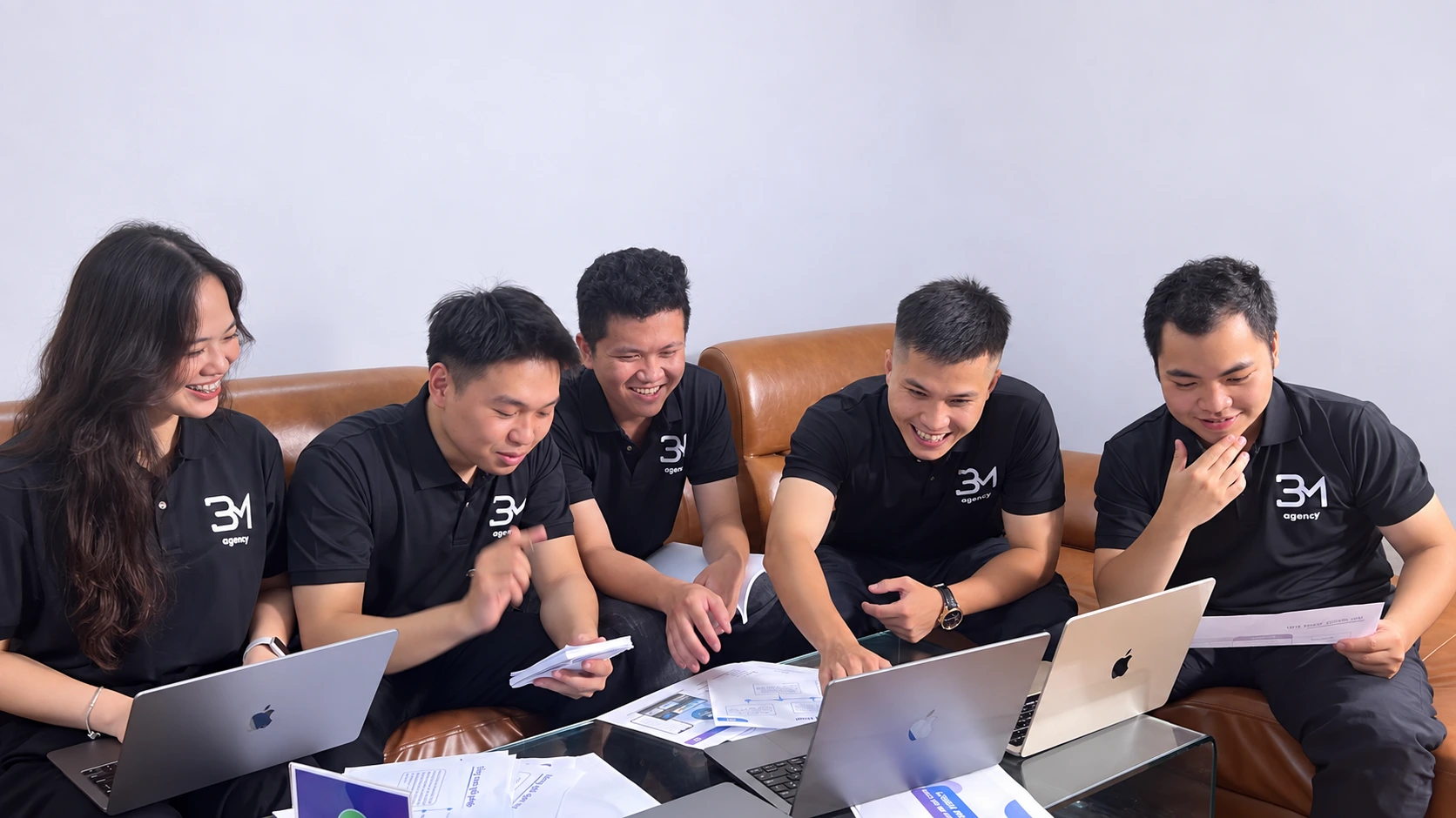 The BM Agency team reviewing documents and working together on a computer