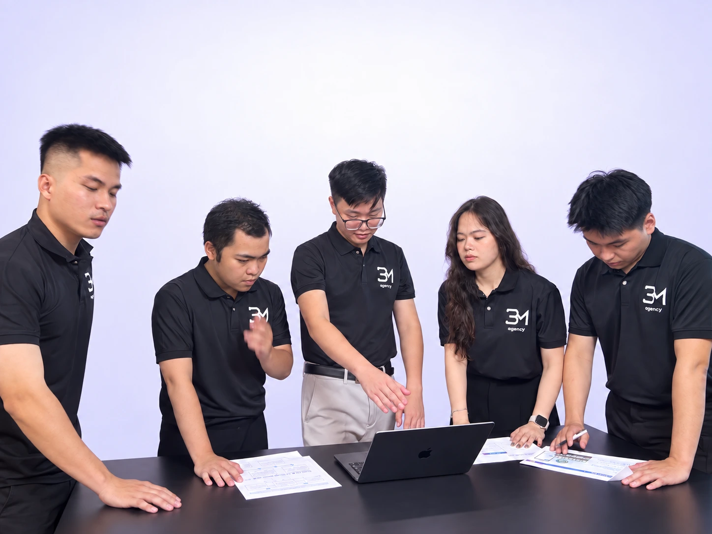 The BM Agency team discussing documents and work around a laptop